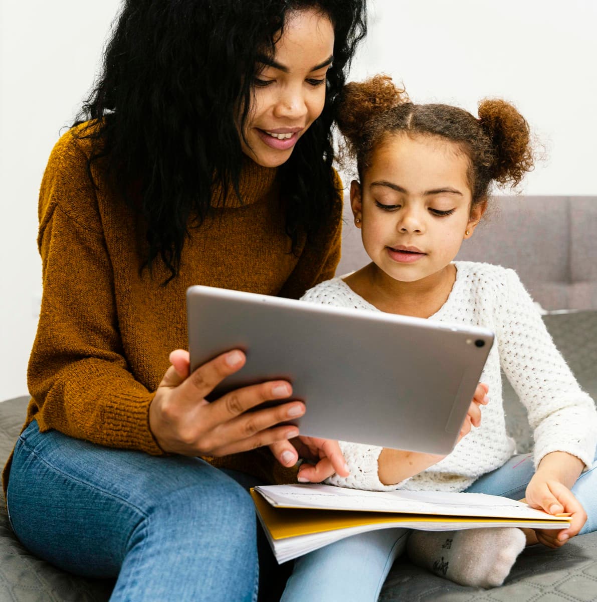 An older sister helping a younger learner with online school